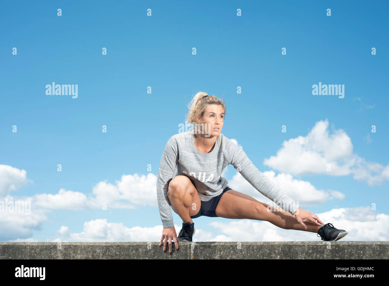 Frau macht eine Kniebeuge Bein Strecken zu passen Stockfoto