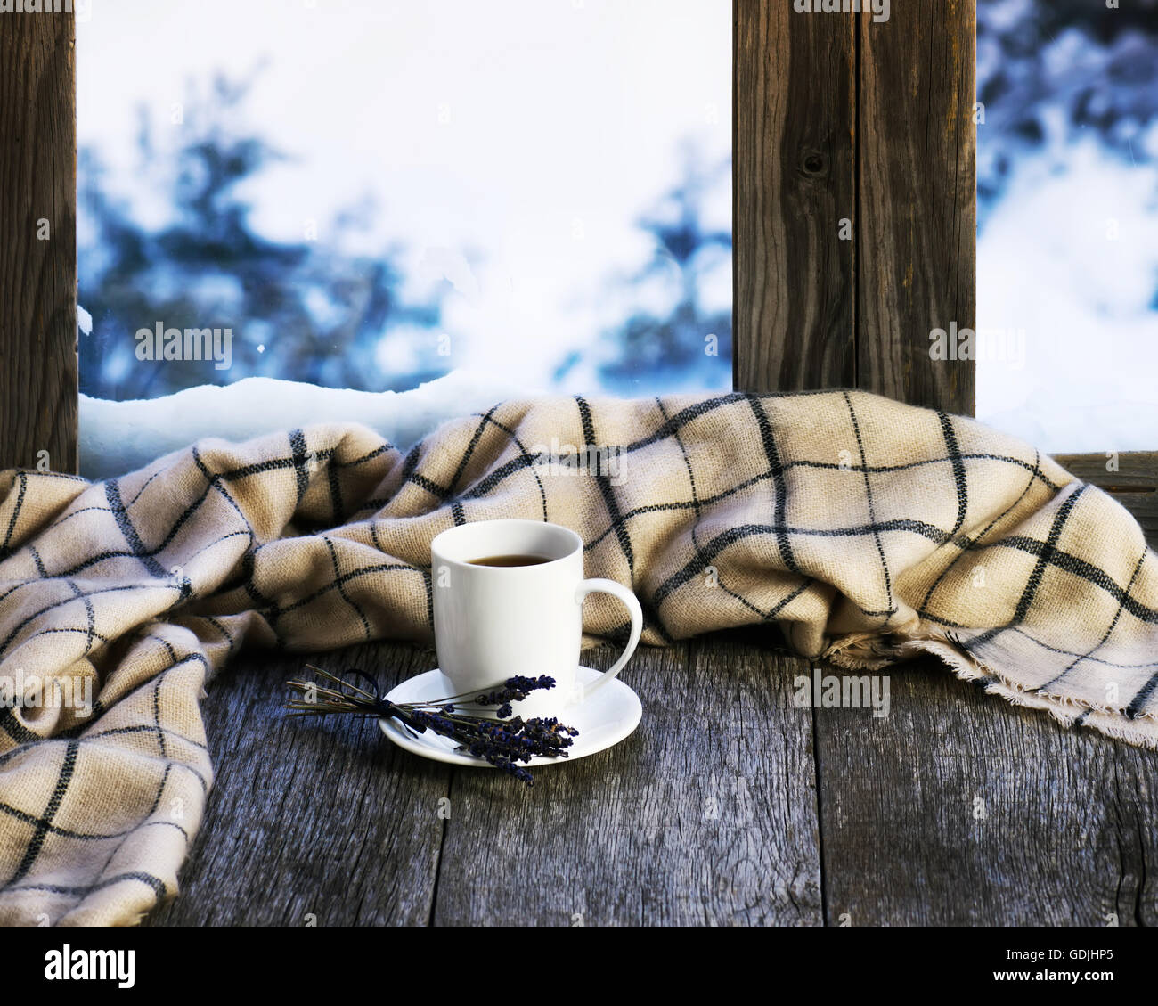 Weiße Tasse Kaffee oder Tee, Lavendelblüten und wollene Plaid auf stilisierte hölzerne Fensterbrett gelegen. Winter-Konzept der Komfort Stockfoto