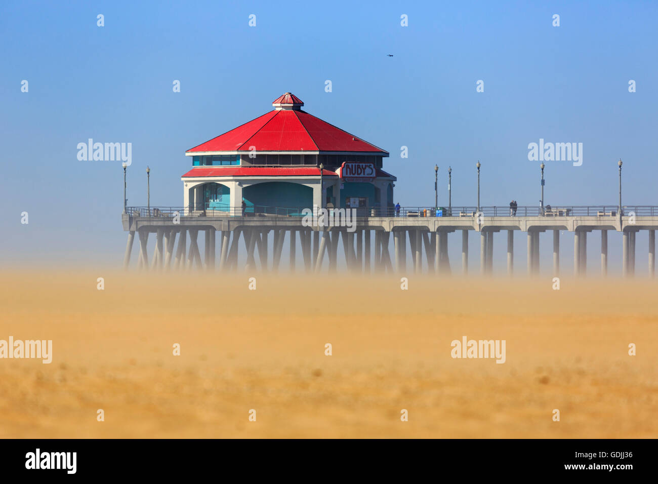 Starker Wind kicks bis der Sand am Huntington Beach und Pier Stockfoto