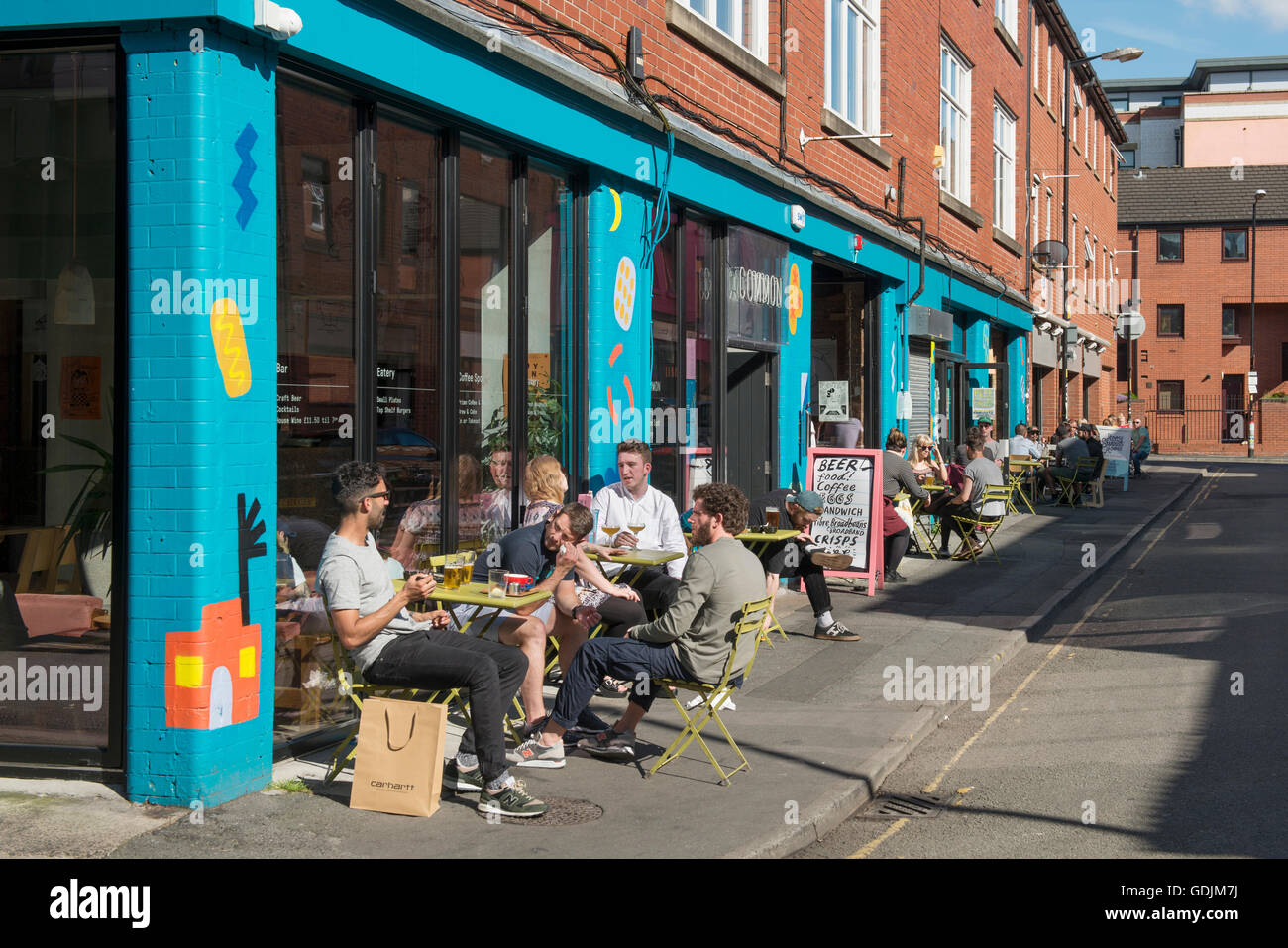 Menschen, die einen Drink vor gemeinsamen Bar befindet sich am Rand Straße in die Northern Quarter Viertel von Manchester. Stockfoto