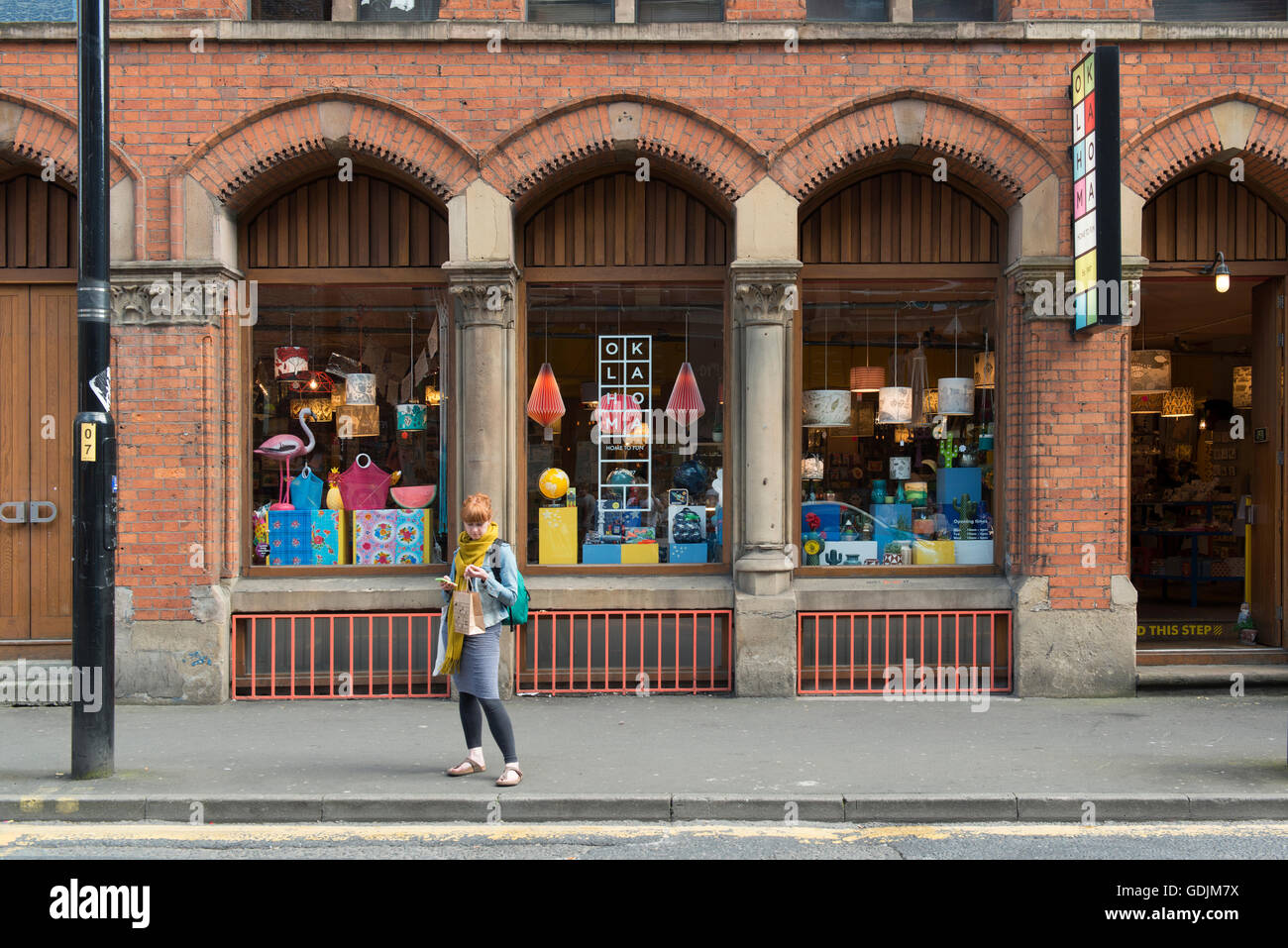 Eine Mädchen wartet draußen Oklahoma Souvenirladen befindet sich an der High Street im Bereich Northern Quarter von Manchester. Stockfoto