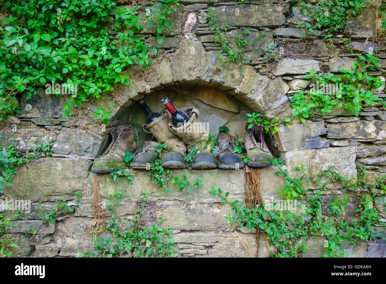 Alte Stiefel und Weinflaschen in Aussparung der Steinmauer Camogli Italien Stockfoto