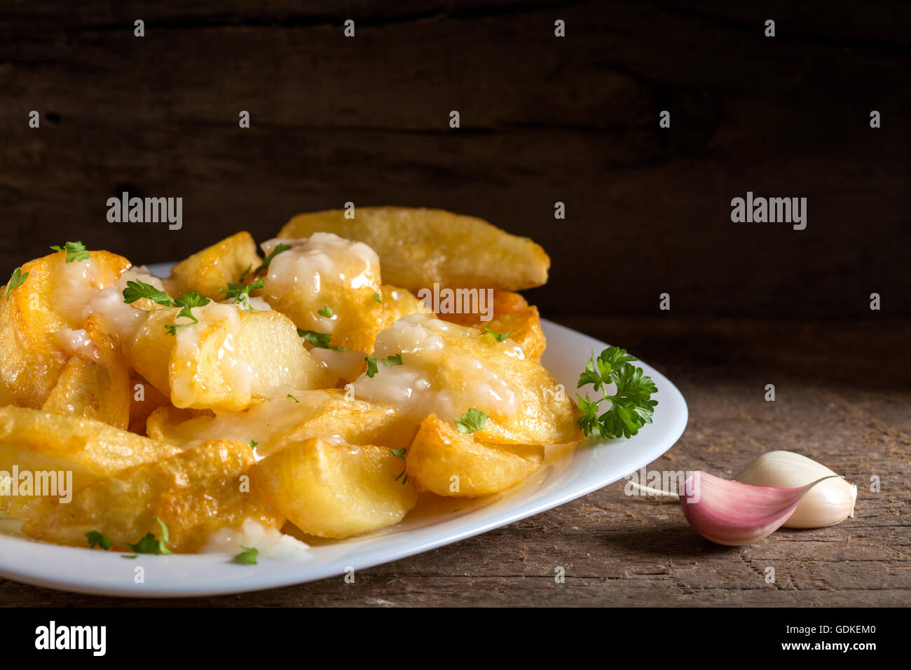 Hausgemachte Pommes Frites (Kartoffeln) mit Knoblauchsauce auf weiße Platte und Holz rustikal Hintergrund Stockfoto