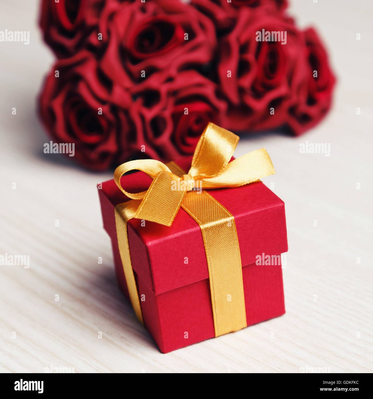 Rote Blumen und Geschenk-Box mit gelben Band Stockfoto