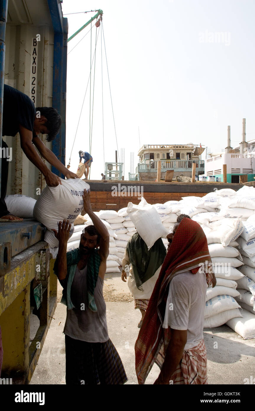 Männer entladen Säcke aus einem Container, Sharjah, Vereinigte Arabische Emirate. Stockfoto