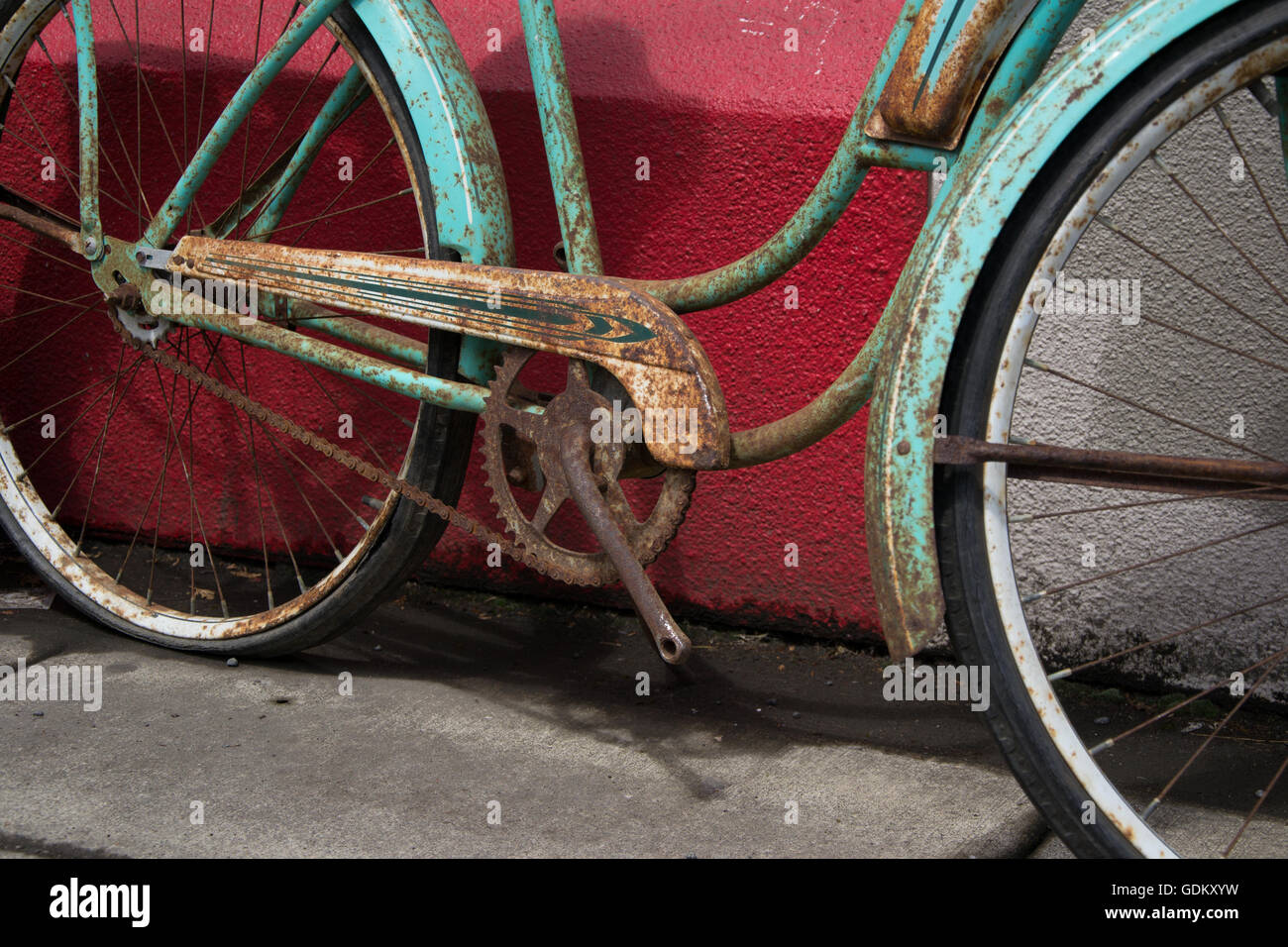 Vintage rostigen Fahrrad ohne Pedale über eine rote Wand Stockfoto