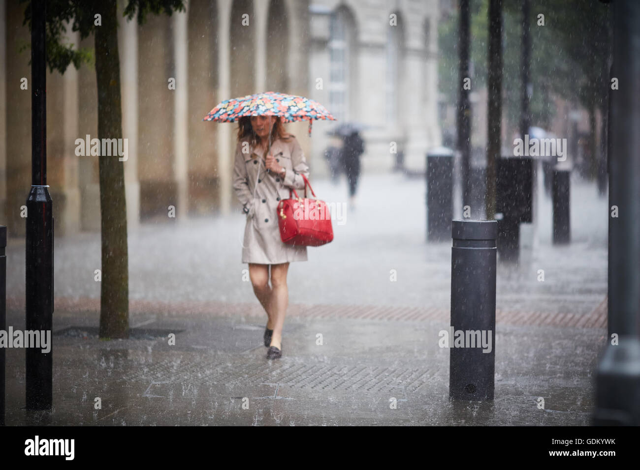 Starkregen in Manchester Stadtzentrum regen Gießen nass regnen einweichen getränkt durch Regenschirm Prellen der Estrich Stockfoto