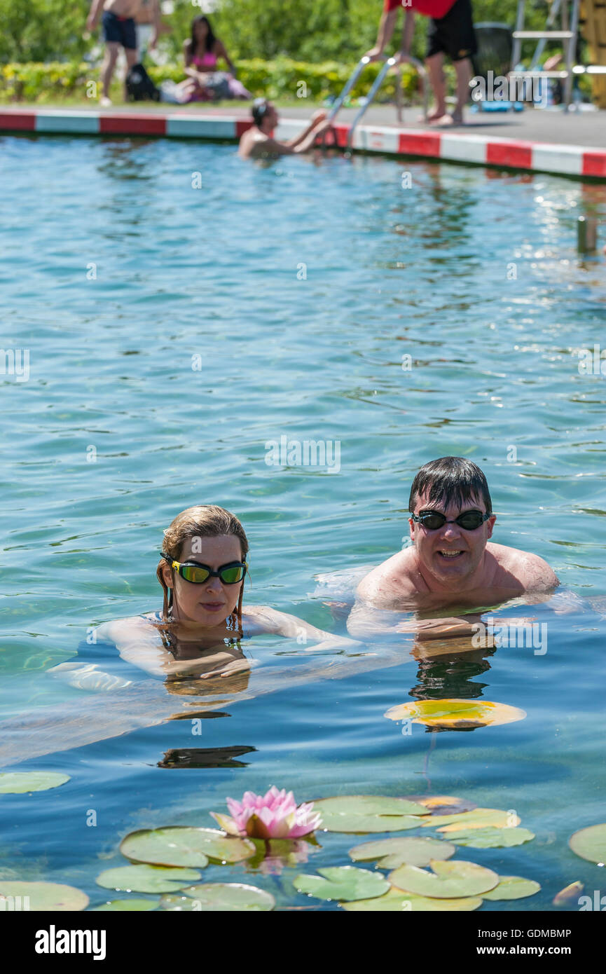 London, UK.  19. Juli 2016.  Lokalen Büroangestellte in ihrer Mittagspause, Evelyn und Sean, genießen Sie das kühle Nass des Kings Cross Teich am heißesten Tag des Jahres so weit mit Temperaturen voraussichtlich 35 C in der Hauptstadt zu erreichen.  Großbritanniens erste jemals vom Menschen verursachte Süßwasser öffentliches Badeteich ist ein Stück der innovativen Land-Art in eine funktionierende Konstruktion Grundstücksfläche von London Kings Cross von Schleim Architekten entworfen. Bildnachweis: Stephen Chung / Alamy Live News Stockfoto