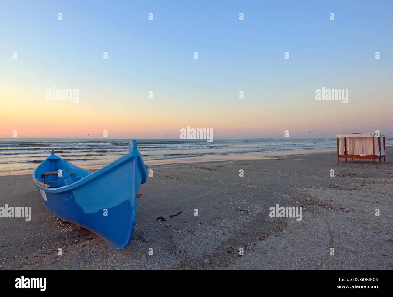 Sonnenaufgang am Strand mit blaue Boot Stockfoto