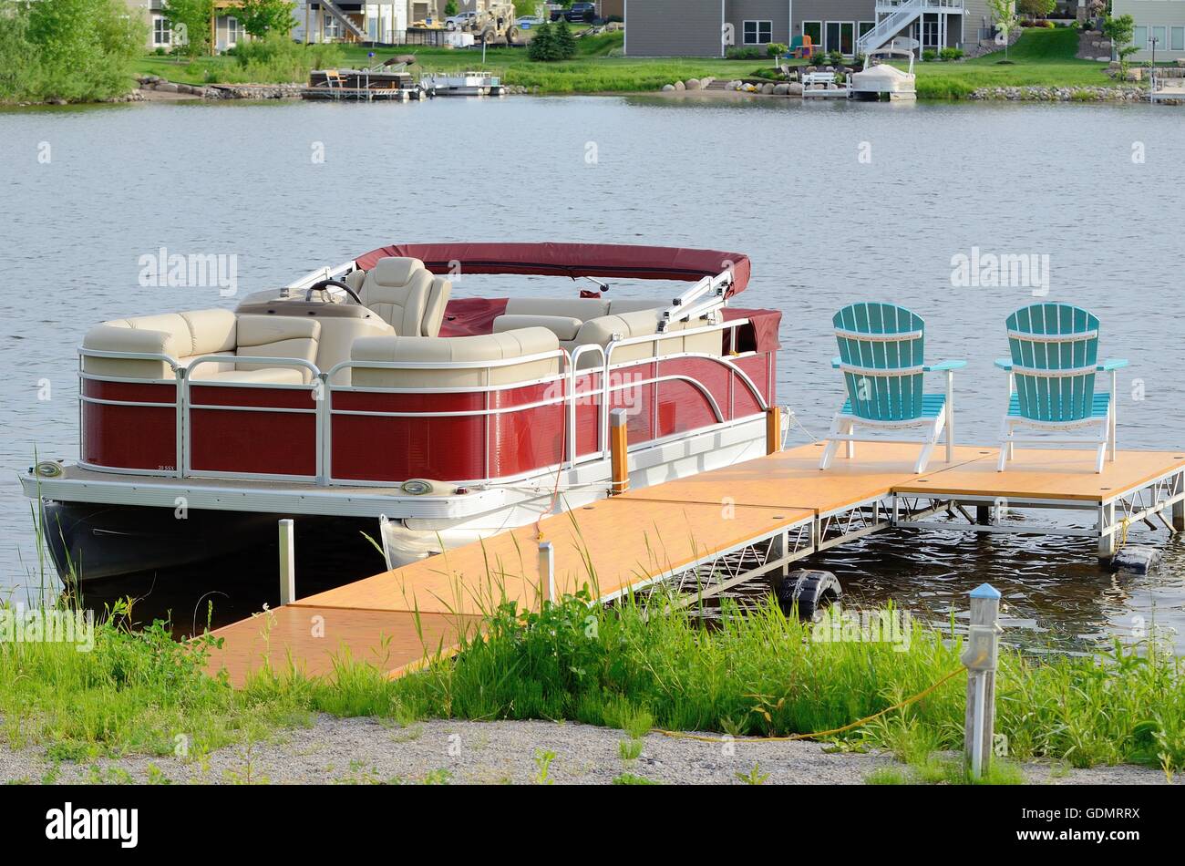 Roten Ponton-Boot gebunden an ein Dock mit zwei Stühlen Stockfoto