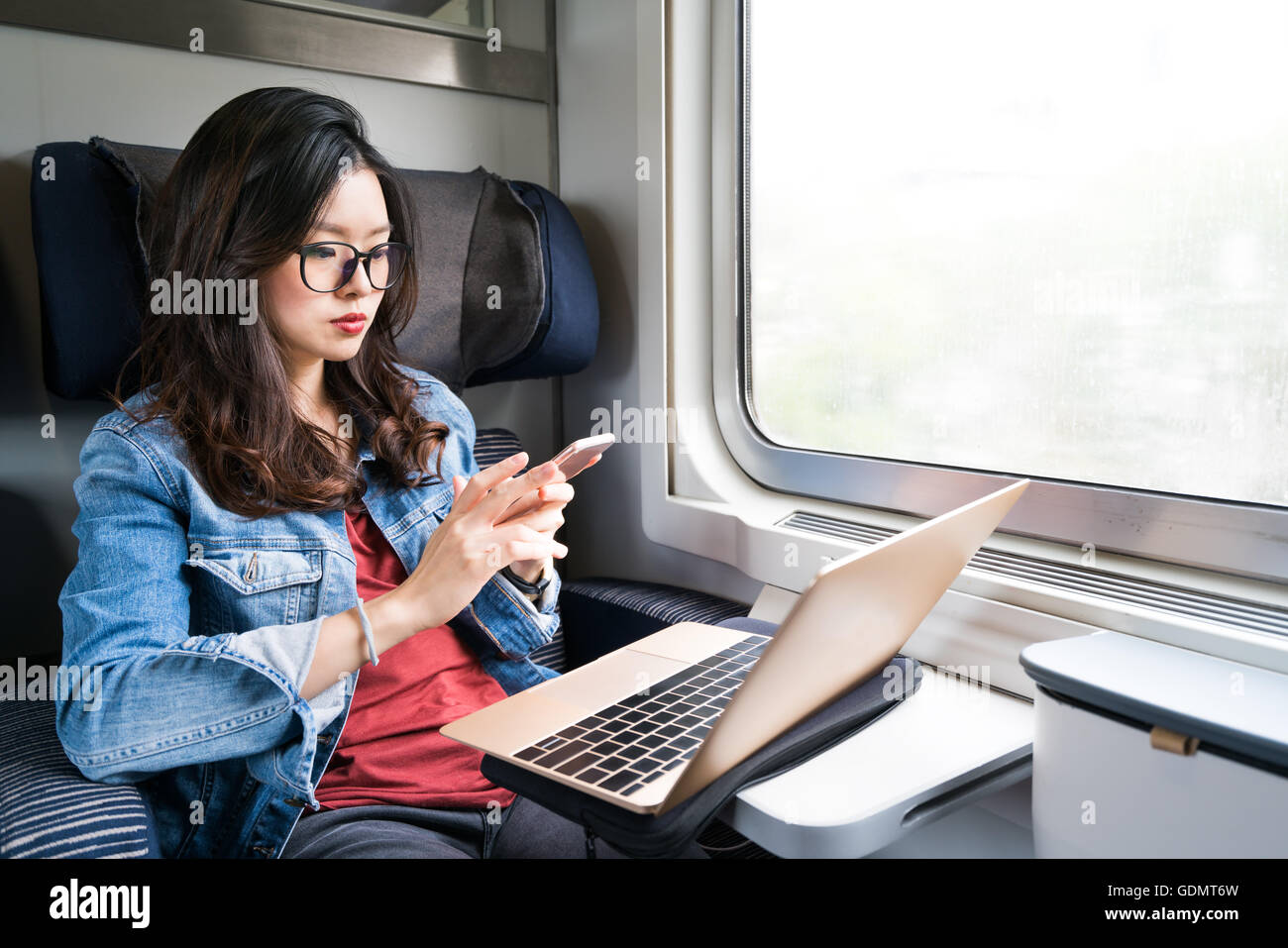 Süße Asiatin mit Smartphone und Laptop auf Zug, Textfreiraum auf Fenster, Business-Reisen oder Technologie-Konzept Stockfoto