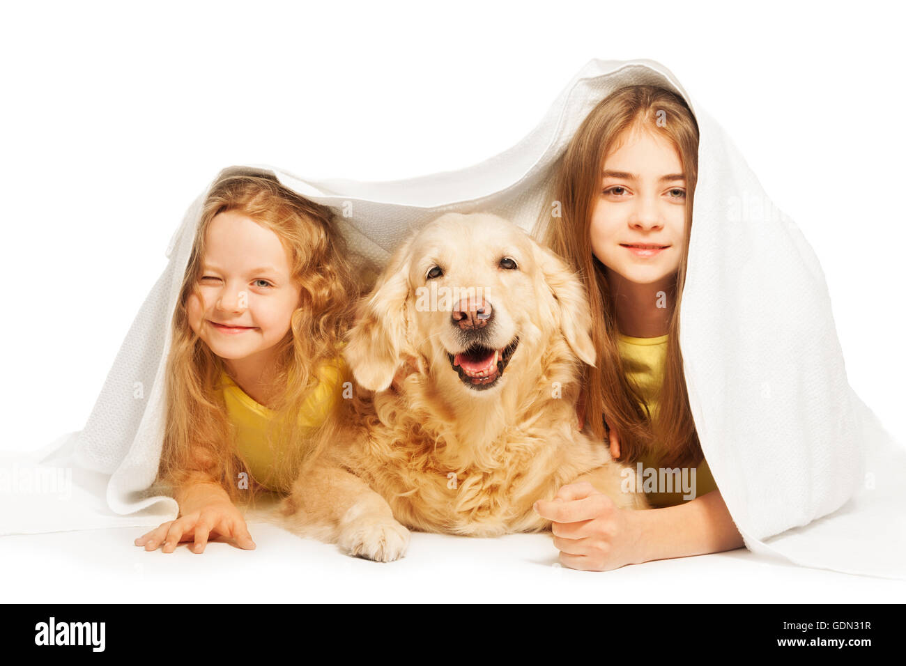 Niedlichen Mädchen versteckt unter der weißen Decke mit Hund Stockfoto