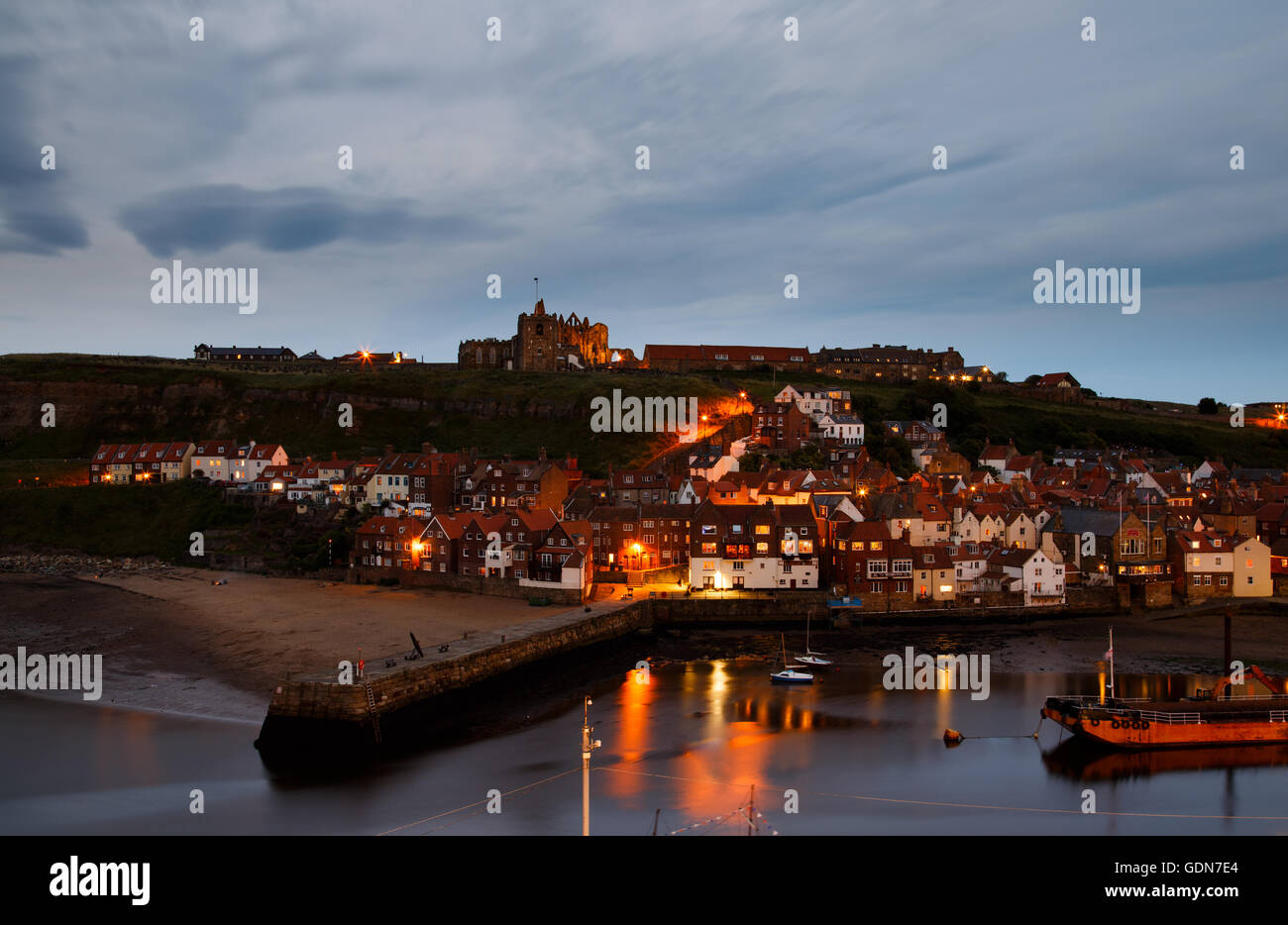 Die Ruinen von Whitby Abbey, mit dem Hafen im Vordergrund, in der Dämmerung. Stockfoto