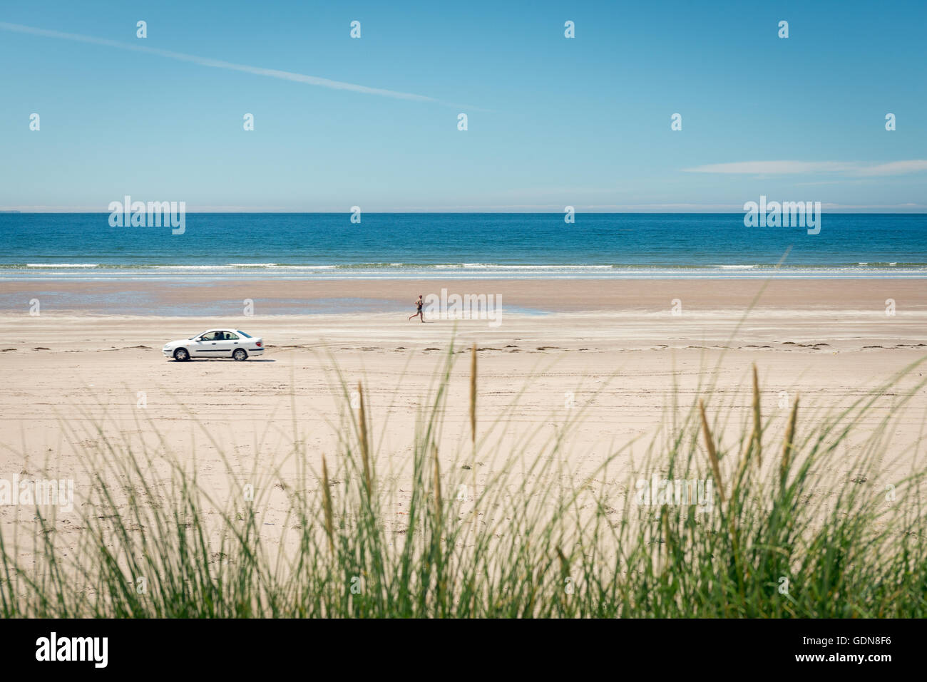 Irland Beach Inch Strand und einsame Mann Joggen und Auto an einem Strand in Inch Beach, County Kerry, Irland Stockfoto