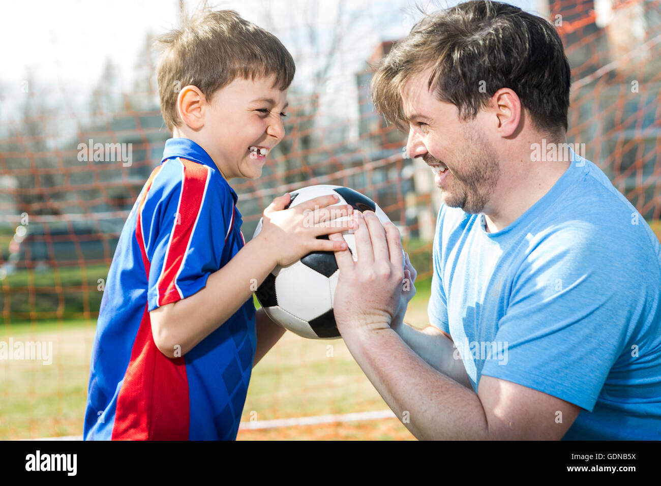 Mann mit Kind Fußball spielen auf Stellplatz Stockfoto