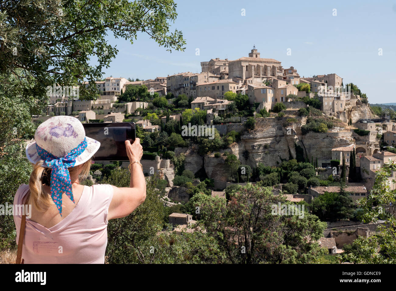 Touristen, die mit dem Fotografieren auf ihrem I-Pad von Gordes eines Dorfes in der Provence Frankreich Stockfoto