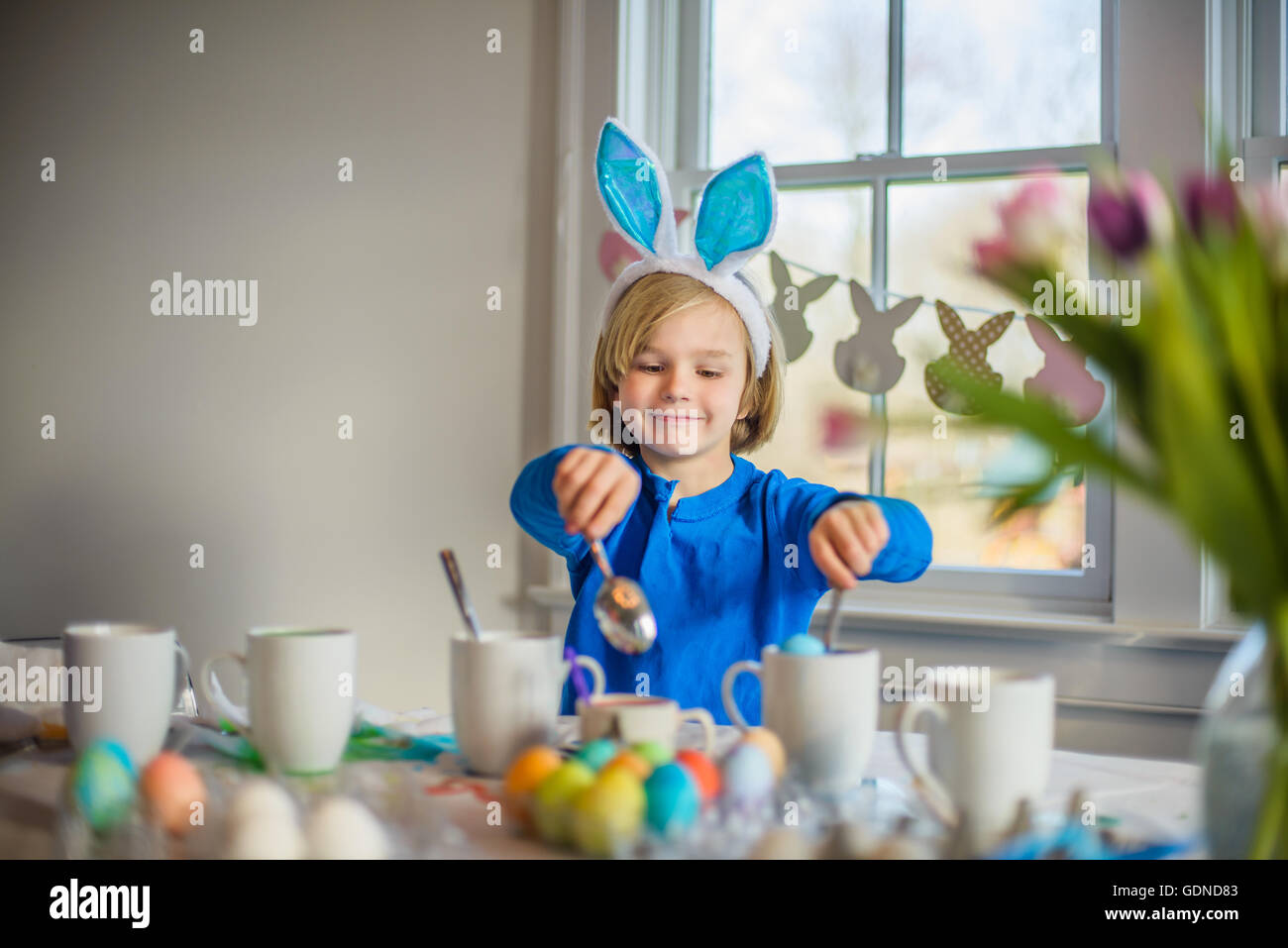 Junge am Tisch tragen Hasenohren dekorieren von Eiern zu Ostern Stockfoto