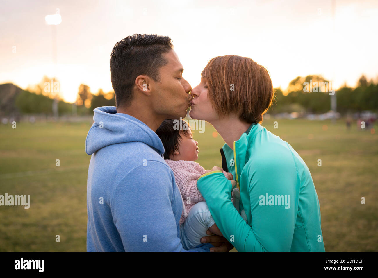 Paar mit Baby, küssen im park Stockfoto