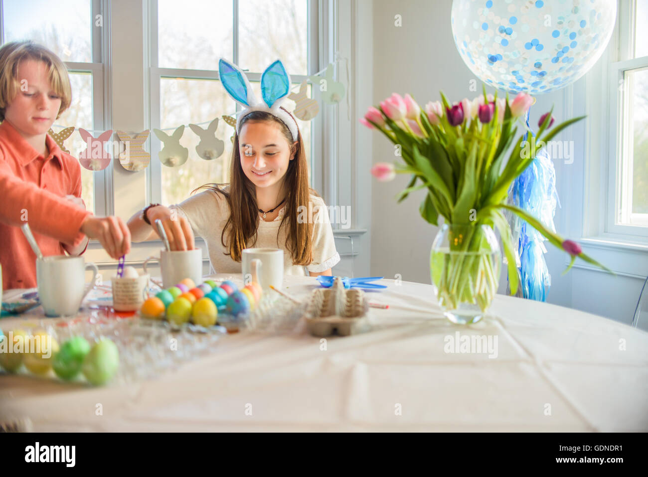 Teenager-Mädchen und Bruder färben hart gekochten Eiern zu Ostern am Tisch Stockfoto