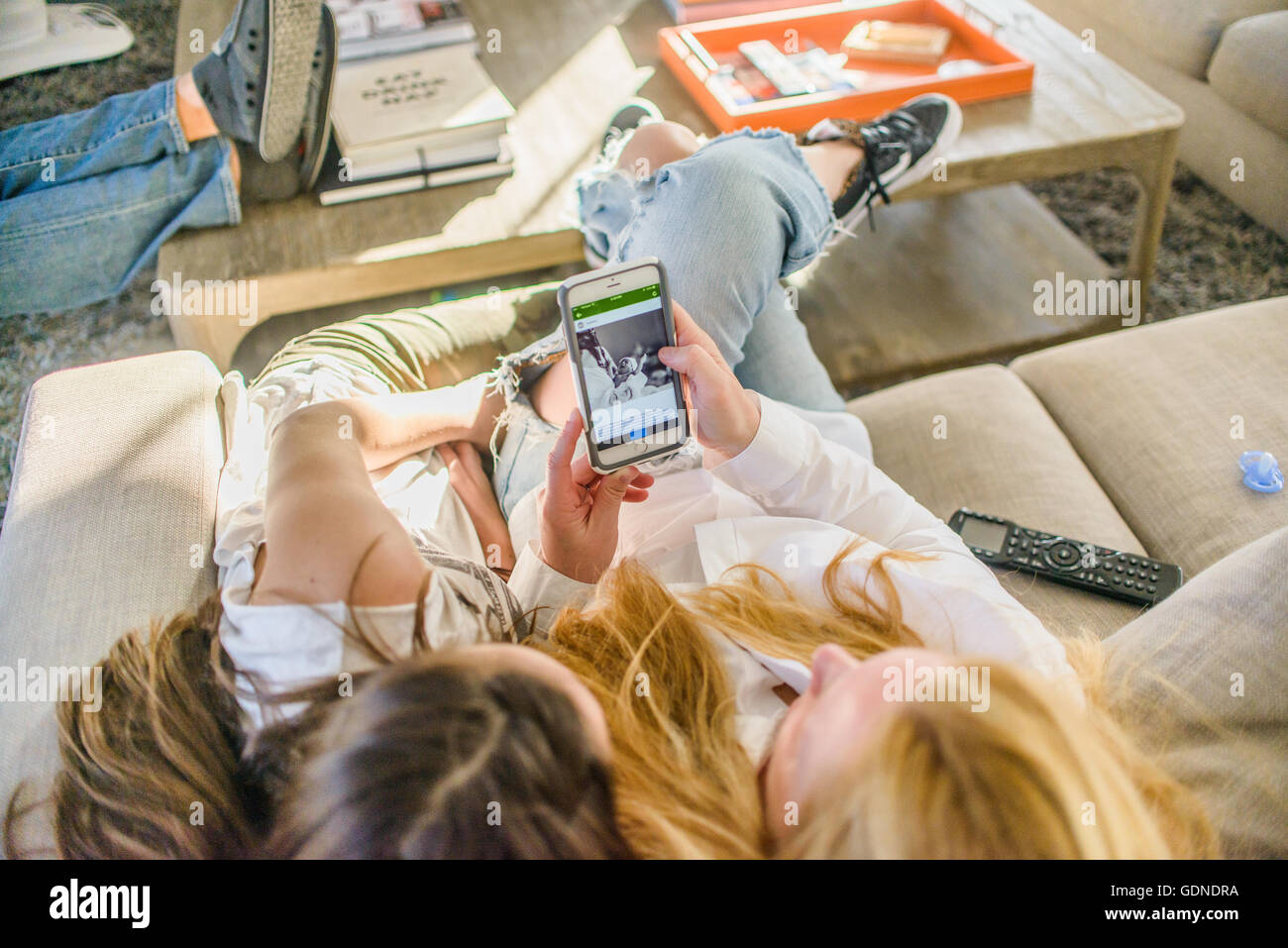 Draufsicht von Mutter und Tochter im Teenageralter auf Sofa suchen neugeborenes Baby Foto auf smartphone Stockfoto