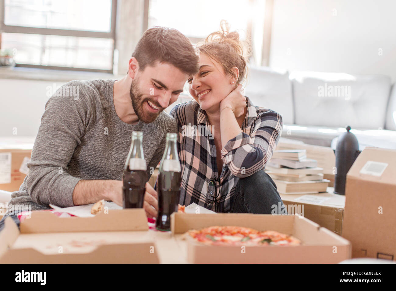 Umzug: junges Paar Essen Pizza im neuen Zuhause, umgeben von Feldern Stockfoto