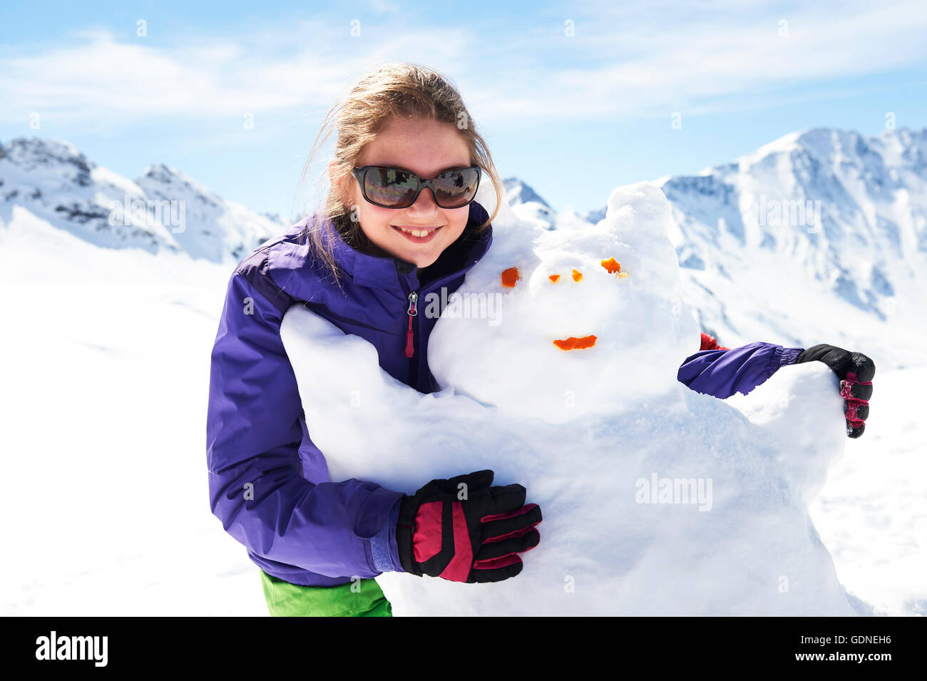 Porträt von Teenager-Mädchen umarmt Schneemann Stockfoto
