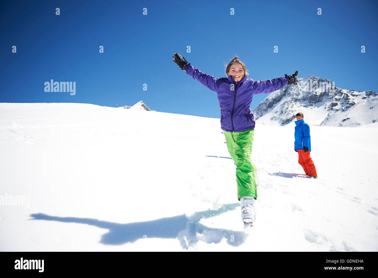 Teenager-Mädchen im Schnee, ausgestreckten Armen springen Stockfoto