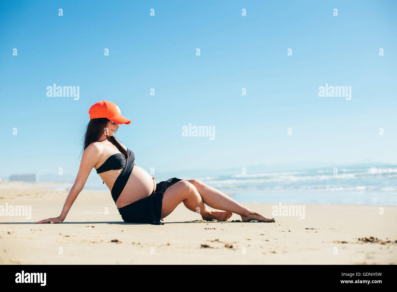 Werdende Mutter auf dem Sand liegen Stockfoto