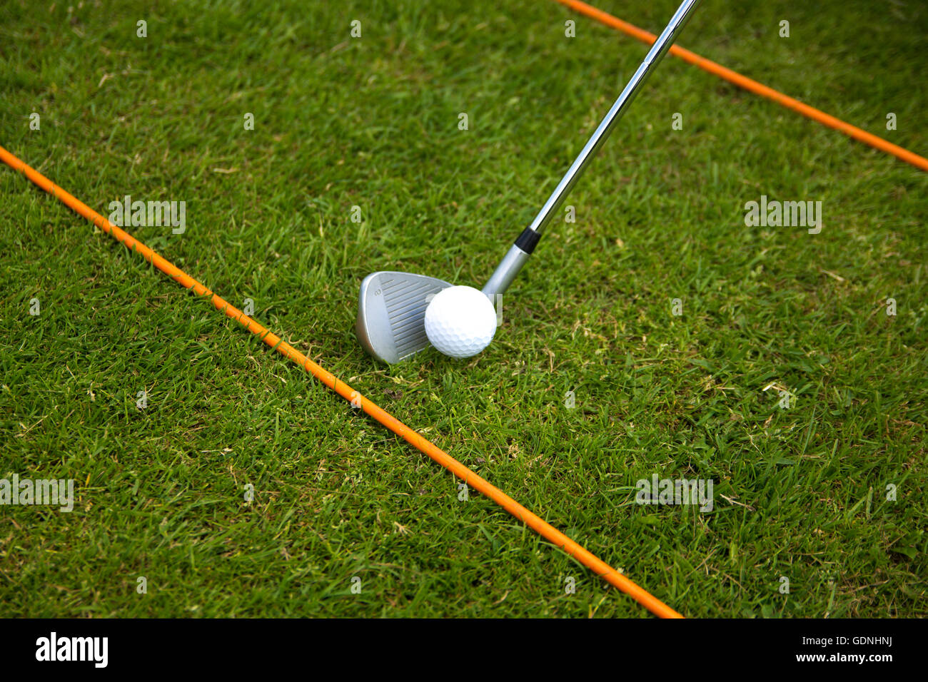 Ein Golfclub hinter einem neuen Pfingstmontag Golfball zwischen einer Reihe von Golf-Praxis ruht klebt. Stockfoto
