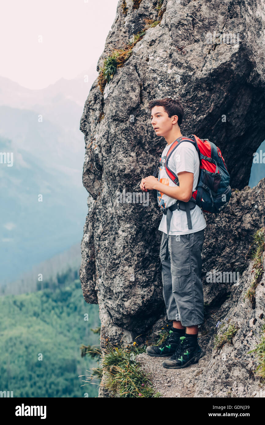 Junge stehend auf den Felsen in den Bergen und mit Blick auf ein Tal Stockfoto