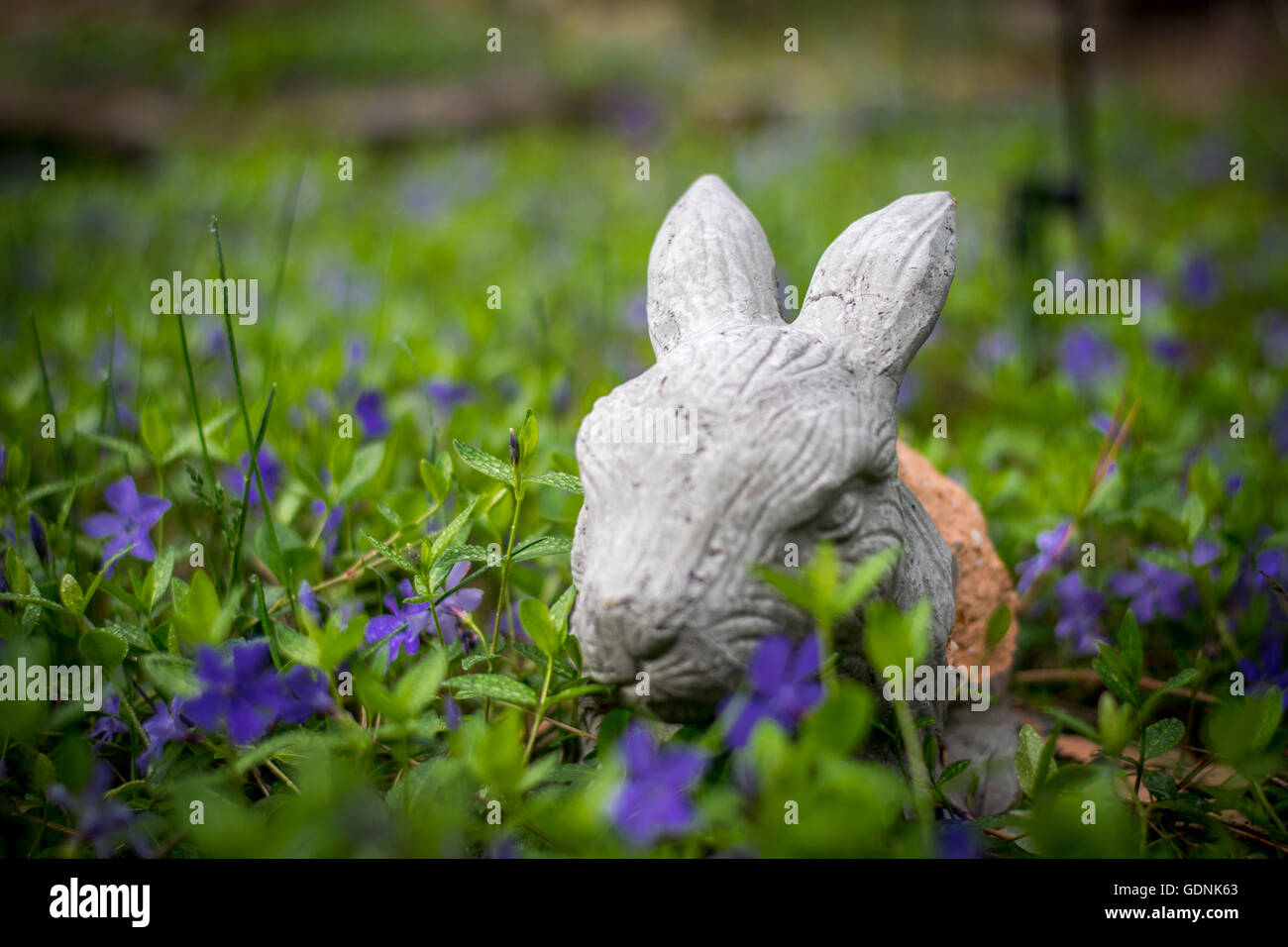 Hase-Skulptur, die versteckt in einem Blumengarten Stockfoto