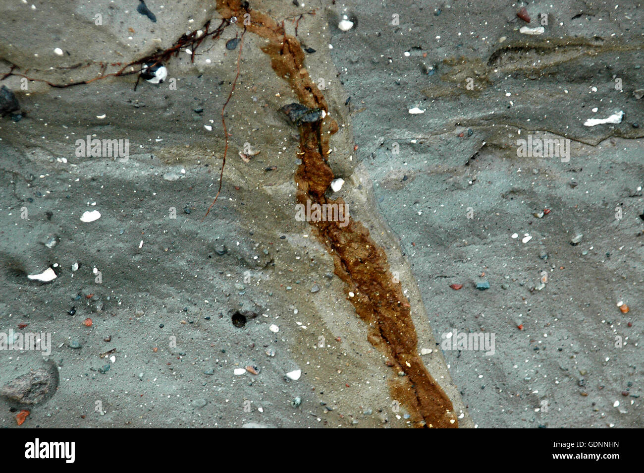 Ein Riss in einer Ton-Wand hat den Eisengehalt in den Ton zu bekommen oxidiert und damit braun verursacht. Stockfoto