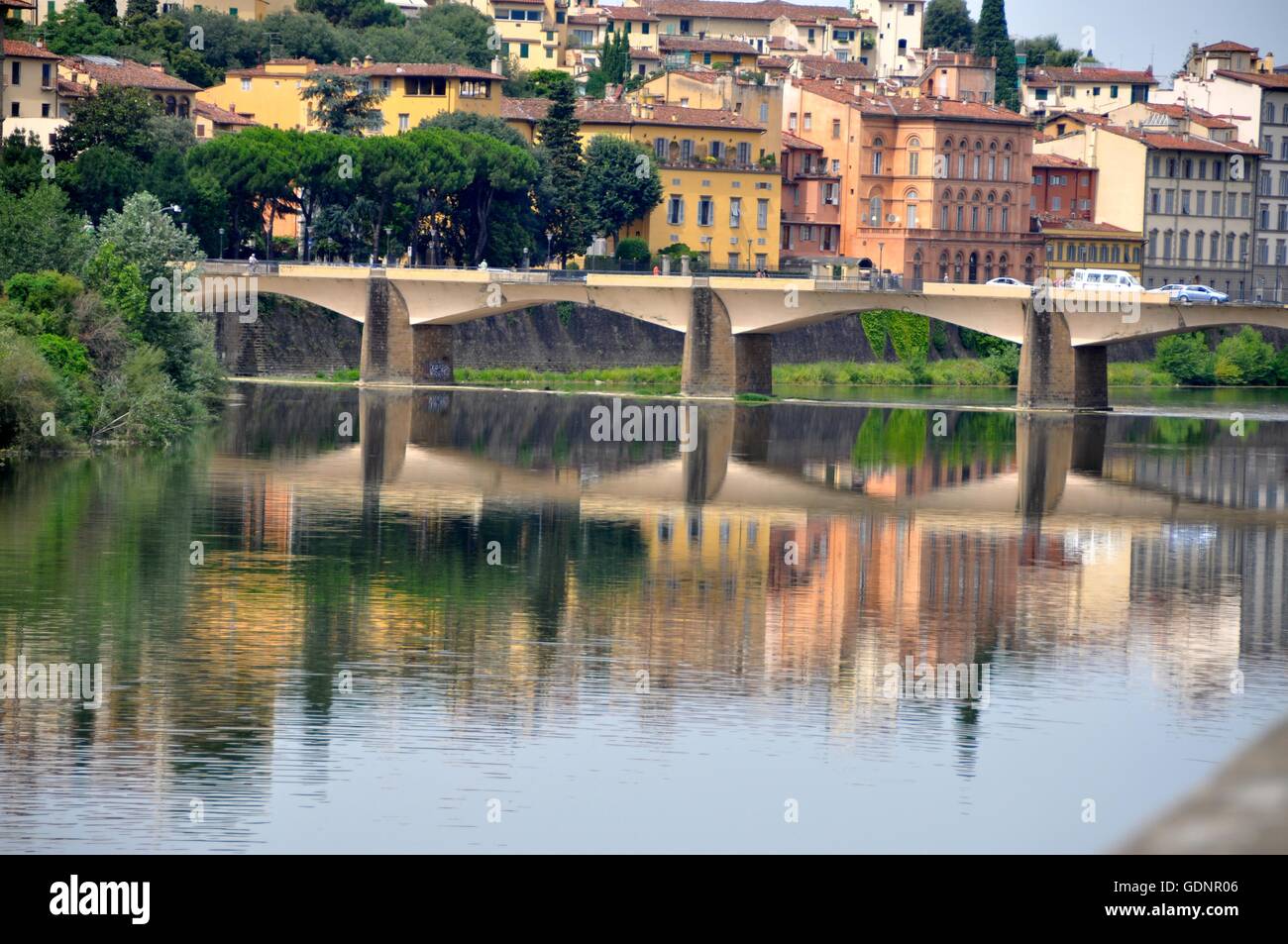 Ansicht von Gebäuden und Brücke und ihre Reflexion über ruhige Gewässer des Flusses Arno in Florenz an einem heißen Sommertag. Stockfoto