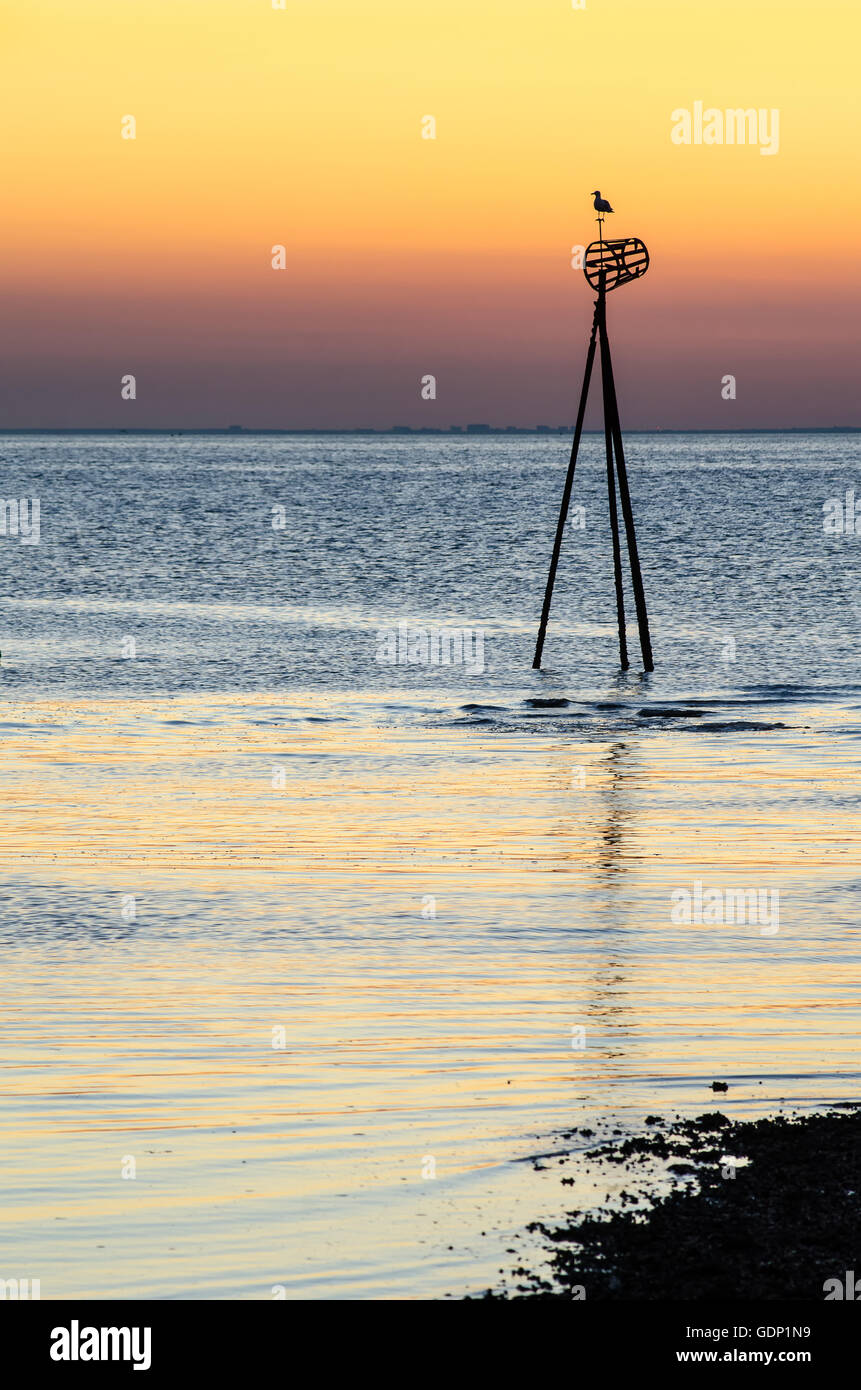 Sonnenuntergang am Hampton in der Nähe von Herne Bay, Kent. Ein Seezeichen ist durch das Leuchten der Sonne abhebt. Stockfoto
