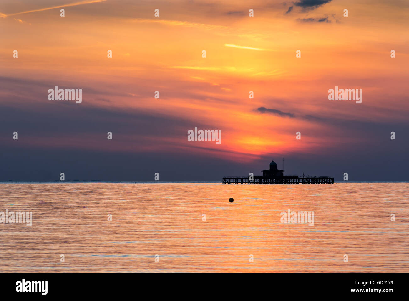 Die untergehende Sonne spiegelt über das ruhige Meer an Herne Bay, Kent, UK Stockfoto
