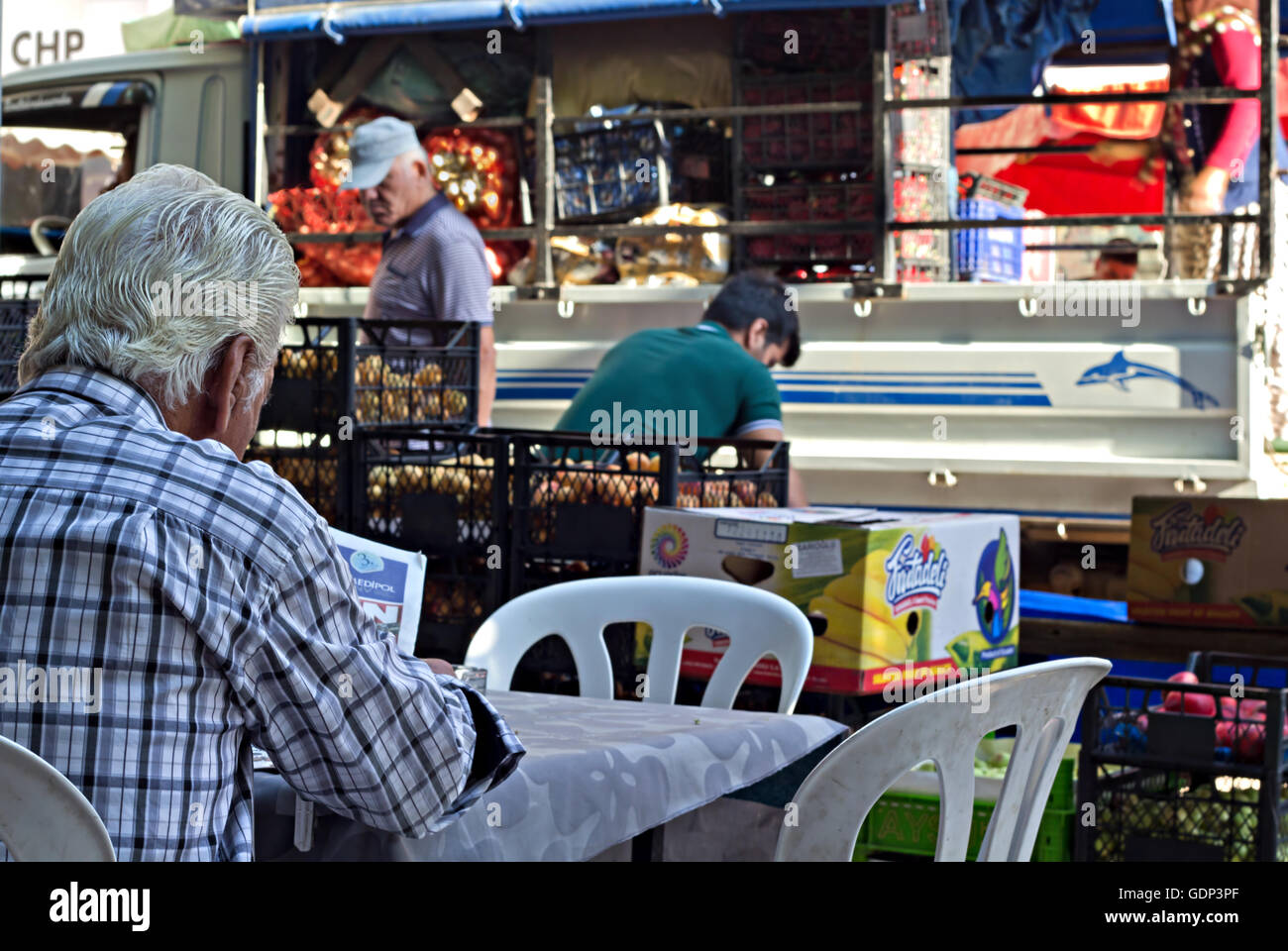 Ein Mann liest seine Morgenzeitung, während Standbesitzer in Türkisch Straßenmarkt einrichten Stockfoto