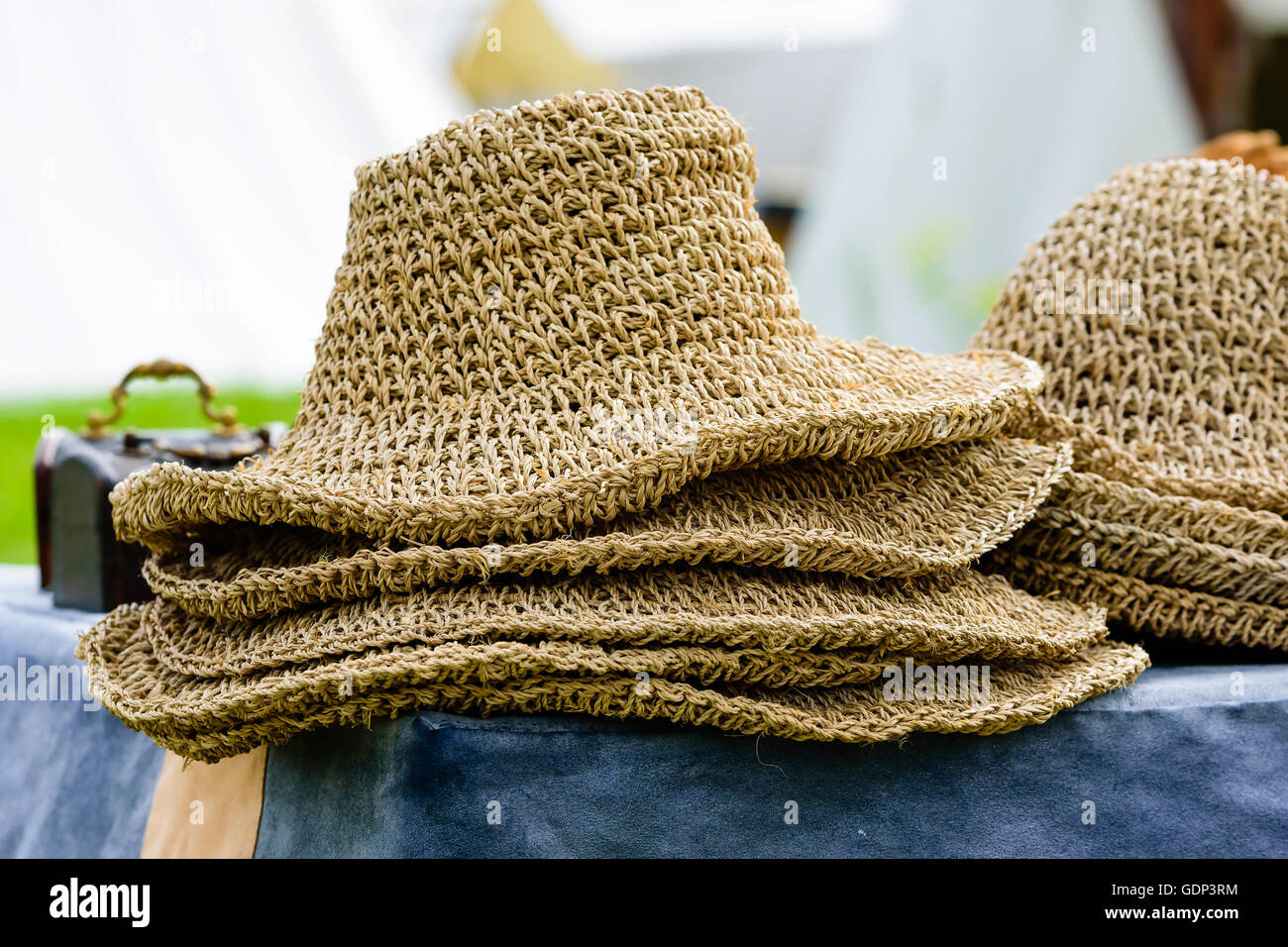 Stapel Hüte hergestellt aus natürlichem Stroh auf einer Tischplatte. Stockfoto