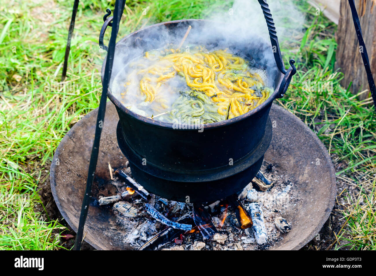 Im freien Hand an Garn in einem Eisentopf Kochen über offenem Feuer sterben. Garn und Kräuter in das kochende Wasser vorhanden. Stockfoto