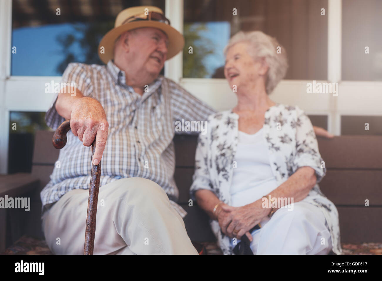 Porträt von senior Brautpaar sitzen auf einer Bank vor ihrem Haus. Älteres Ehepaar entspannen im Freien lieben. Stockfoto