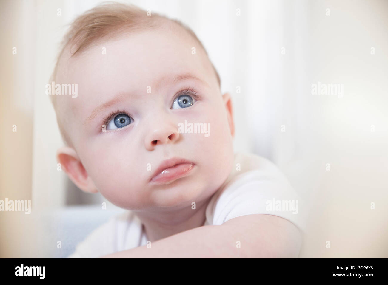 Porträt von blue eyed Baby junge starrte aus Krippe Stockfoto