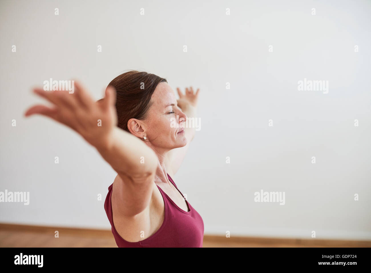 Seitenansicht der Frau in Übung Studio erhobenem Arm, schloss die Augen in Yogaposition Stockfoto