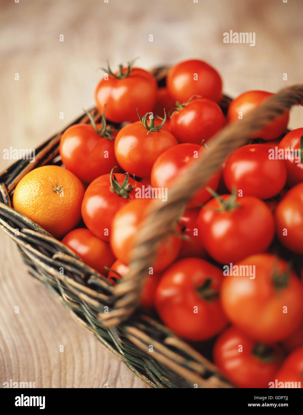 Lebensmittel, Obst und Gemüse, frische Strauchtomaten und eine Orange in einem Weidenkorb Stockfoto