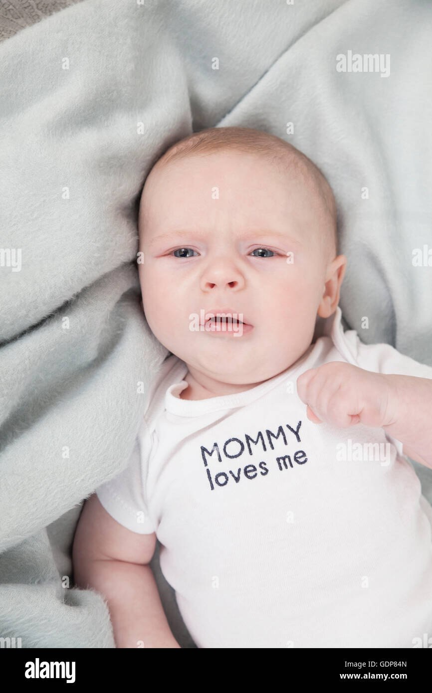 Baby Boy auf der Decke liegend, Anzug sagt "Mama liebt mich" Stockfoto