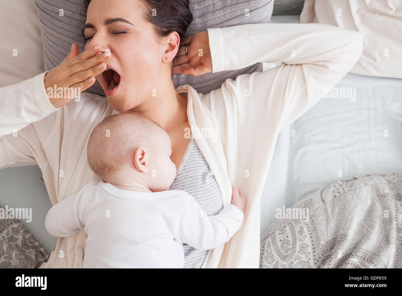 Babyjungen schlafen auf Mutter, Mutter Gähnen Stockfoto