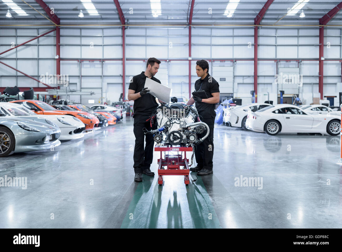 Ingenieure mit Motor zur Reparatur im Rennsport Autofabrik Stockfoto