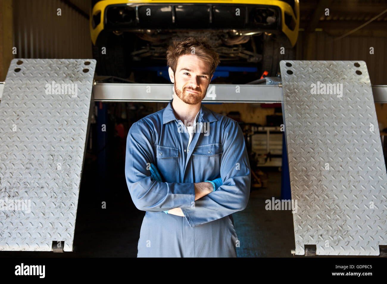 Porträt von männlichen Mechaniker hinter Wagenheber in garage Stockfoto