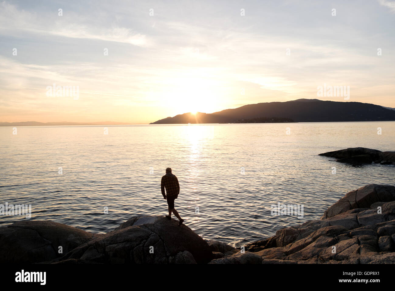 Mitte erwachsener Mann stehen auf Felsen, über See betrachten Rückansicht Stockfoto