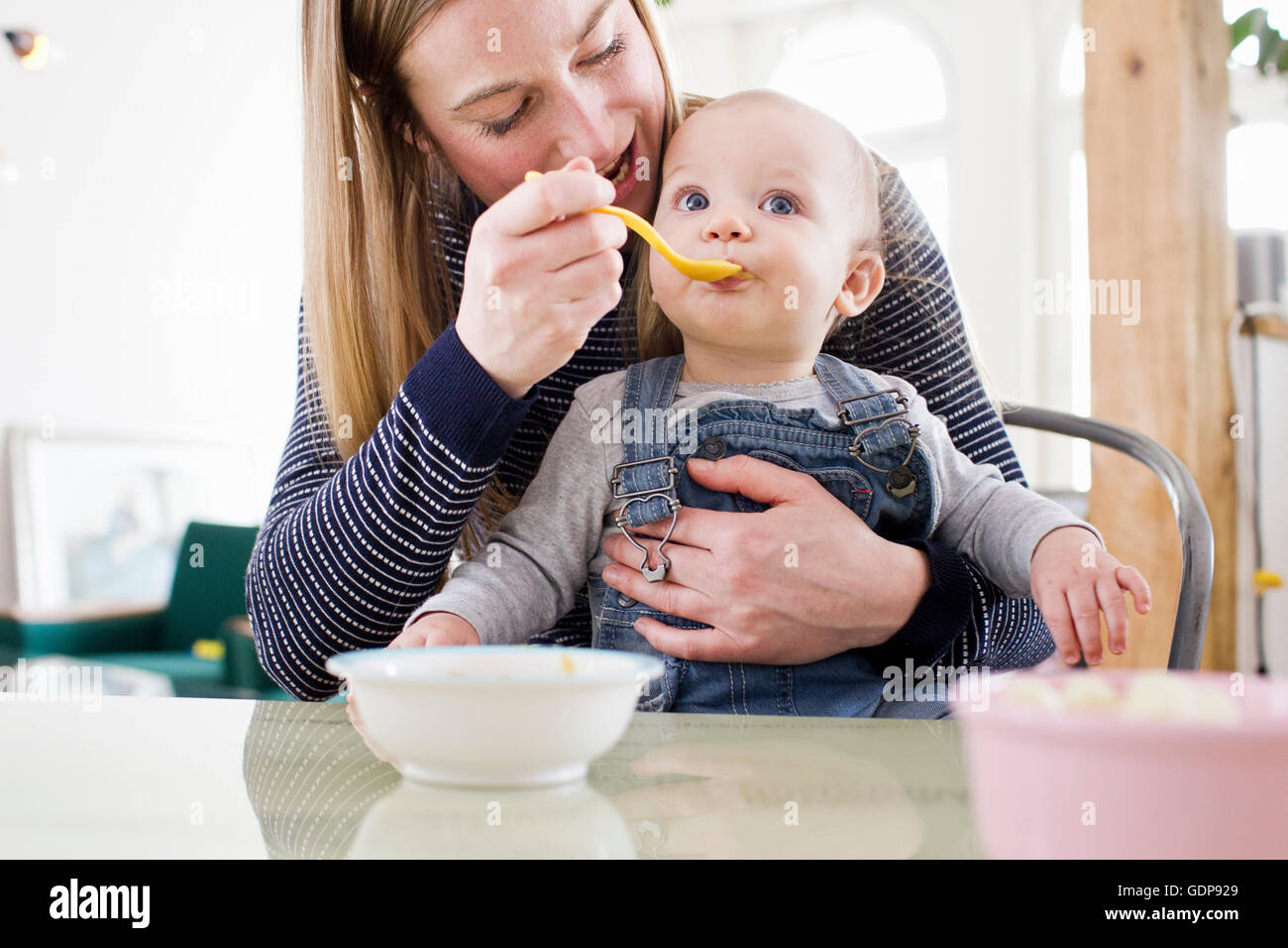 Mitte Erwachsene Frau Fütterung Baby Tochter am Küchentisch Stockfoto