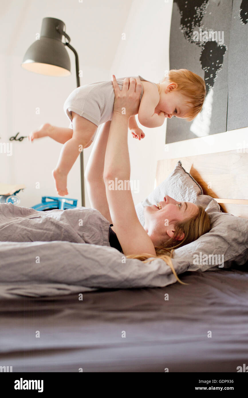 Mitte Erwachsene Frau hält Baby Tochter im Bett Stockfoto