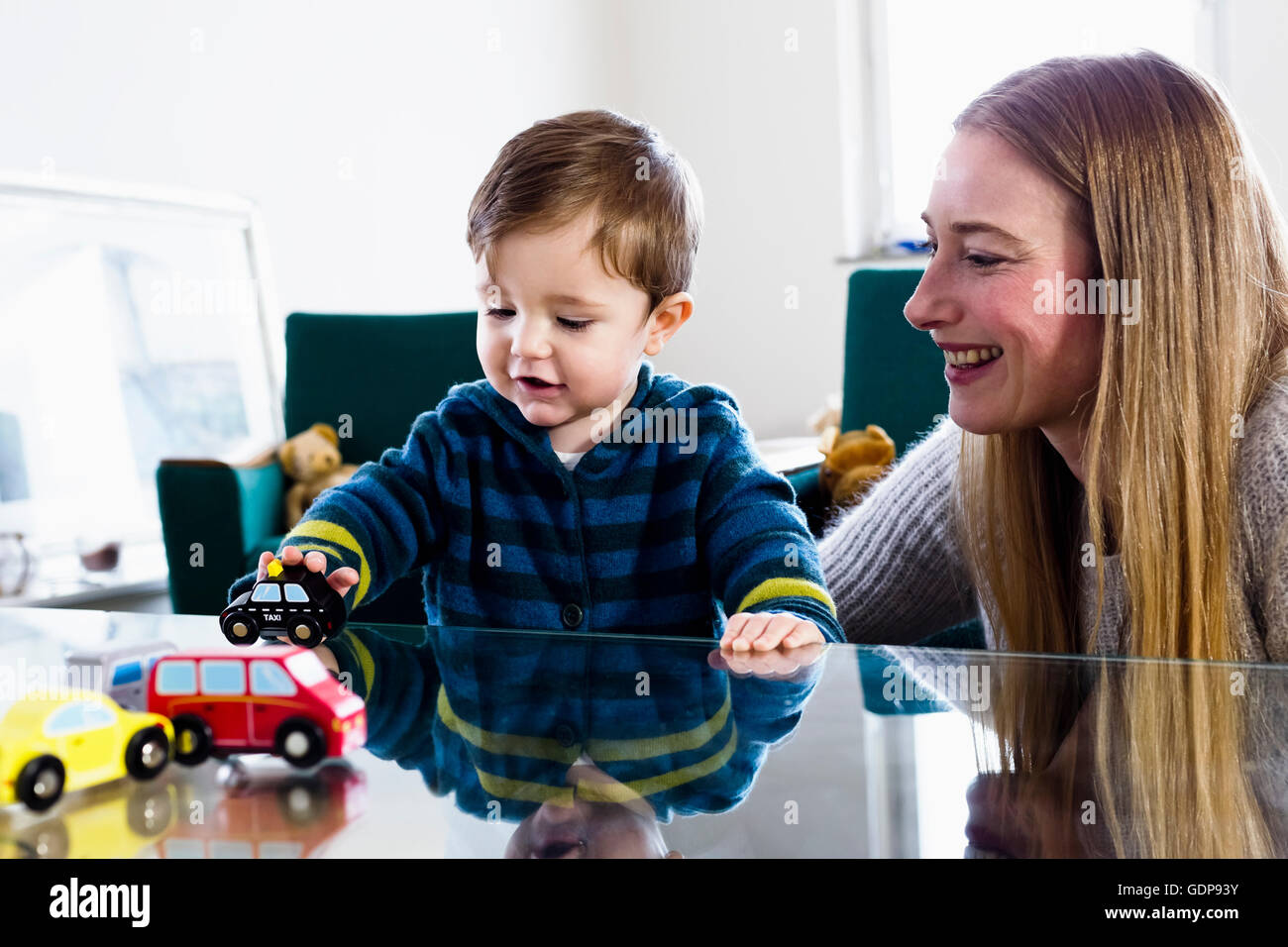 Mitte Erwachsene Frau und Baby Sohn spielt mit Spielzeugautos auf Tisch Stockfoto